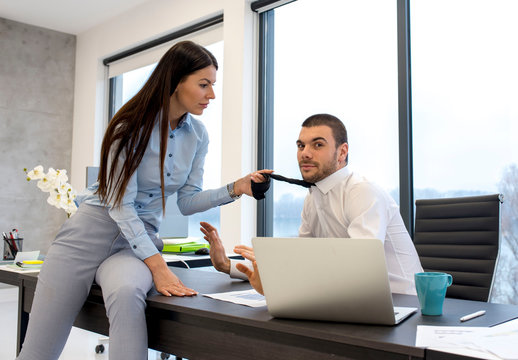 Attractive businesswoman draws colleague for his tie in the office