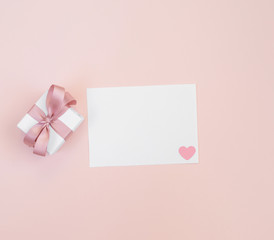 Valentine's day mockup. Greeting card with a gift and white paper on a pastel pink background. Valentine's day concept.