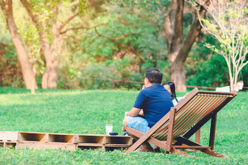 Fototapeta premium Happiness couple on a summer holiday sitting on garden chairs to relax in the public park.