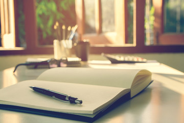 Black pencil on the open book  with glasses and calculator vintage tone and sunset light background