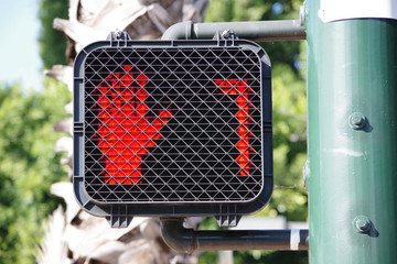 Pedestrian crosswalk traffic signal at a city intersection with a red hand warning to not enter...