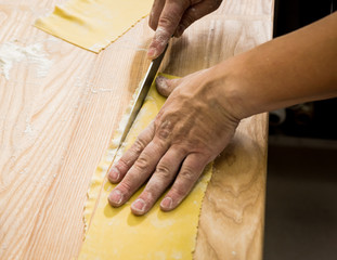 Chef rolling dough with a pasta machine. Pasta maker machine. 