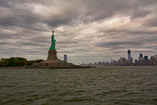 Freiheitsstatue mit Blick auf New York Skyline, bew&ouml;lkter Himmel 