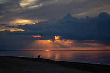 Sea ocean landscape at sunset with volumetric light and human silhouette (god rays) Baltic shore coast at dusk