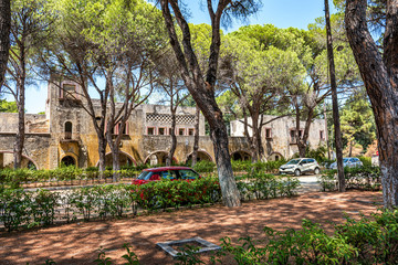 Cars parked in front of deserted building of sanatorium in Italian village of Eleousa (Rhodes, Greece)