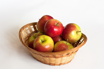 red and yellow apples in a basket on a white background