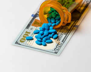 Prescription drug pill bottle with 100 dollar bill isolated on white background. Concept of rising drug, medical, insurance and health care costs