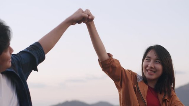 Asian young couple high five gesture while sitting at camp In the midst of nature at daytime