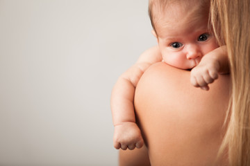 Portrait of a happy little beautiful smiling girl held by the hands of a caring mother. The concept of happy and healthy little children. Advertising space