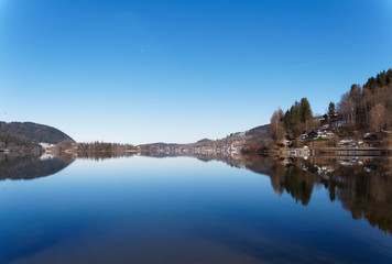  Schliersee in Oberbayern am Horizont mit lichtreflexion. Ort im Winter mit Kirchdorf Sankt Sixtus