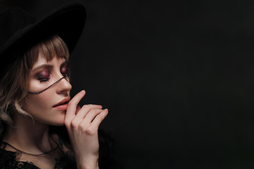 Young beautiful blonde woman in a black hat and dress.