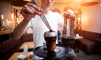 Fototapeta na wymiar Cooking hookah in the bar. Young man with hookah in restaurant