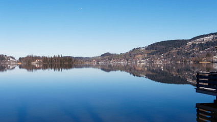 Schliersee in Oberbayern am Horizont mit lichtreflexion, Ort im Winter mit Kirchdorf Sankt Sixtus