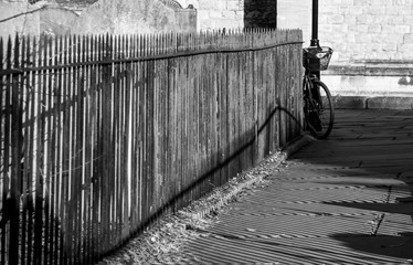 Fototapeta premium Close up of railings and their shadows beside a pathway at St Nicholas Church, Chiswick, London UK, photographed with high contrast in late afternoon on a sunny day in February.