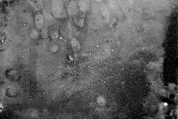 Texture of frozen glass. Wet cold glass on black background.