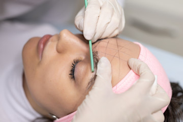 The girl beautician marks with the help of thread eyebrow tattoo. Permanent makeup. Permanent tattooing of eyebrows.