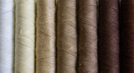 Spools of brown, cream, and white cotton yarn in gradual colour order