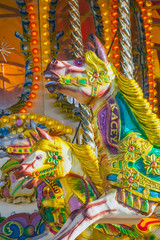 Fototapeta na wymiar Brightly coloured carousel horses at fairground