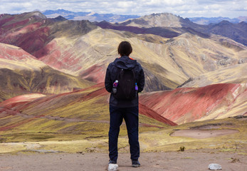 Cusco/Peru: boy admires the beautiful view on the Palccoyo rainbow mountains. Colorful landscape in the andes