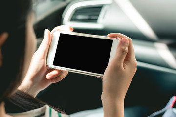 Woman hand holding smart phone in the car with clipping path in screen for easy using.