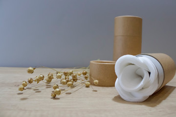 Paper tube with white cotton pads or rounds inside on wooden background. Recycle concept showing how to reuse cardboard packaging for natural cosmetics at home. Front view with copyspace, mockup