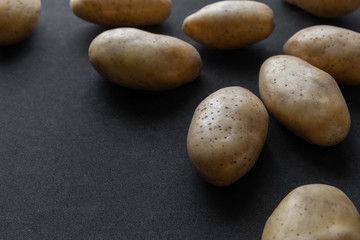 Fototapeta na wymiar Frame of raw organic potatoes on dark background