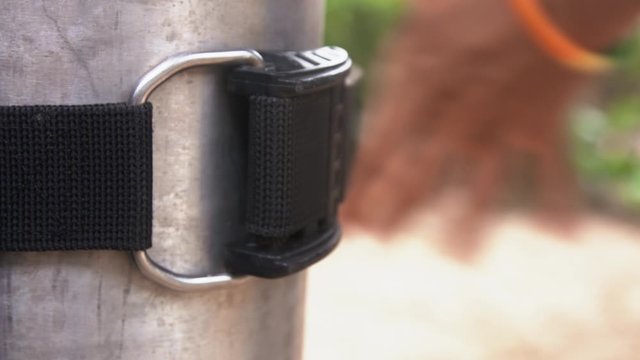 Close-up of hand tightening a strap buckler of a buoyancy control device around gas bottle (BCD), snorkeling equipment