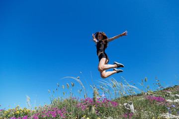 Beautiful, young girl jumps on the slope of a ridge.  Late spring (early summer) Gelendzhik.