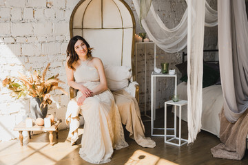 Beautiful young caucasian woman in white lace dress posing for photo in decorated vintage room....
