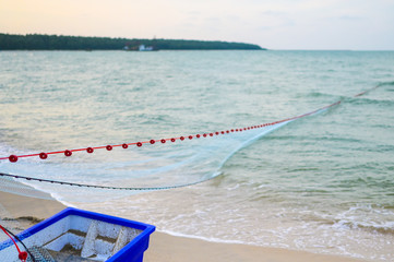 Close view of some blue fishing net floaters on the beach with boat and human while laying nets on the sea