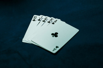 Fototapeta na wymiar Royal flush of clubs. Winning poker hand on a dark table. Poker game concept