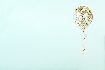 Flying balloon with shiny gold confetti and ribbon on light blue background. Sparkles wallpaper decor. Happy birthday, valentine, wedding invitation postcart background. © lara-sh