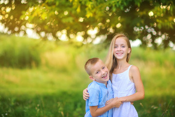 Fototapeta premium Cute children are walking in the evening park. Hug and smile. Children relax and play outdoors. Childhood.