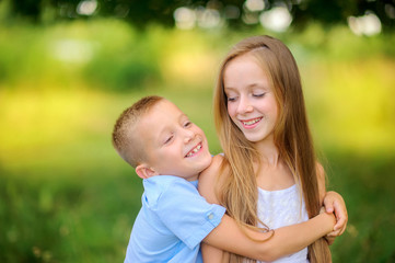 Cute children are walking in the evening park. Hug and smile. Children relax and play outdoors. Childhood.
