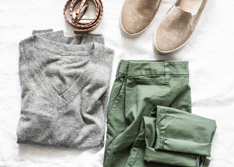 Women's clothing on a light background, top view. Suede shoes, grey pullover, pant, belt clothing for walking. Fashion concept, flat lay