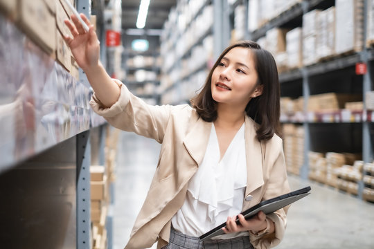 Pretty Worker Checking Stock In The Warehouse. Asian Beautiful Young Woman Worker Of Furniture Store.Businesswoman Using Tablet In Distribution Stock.