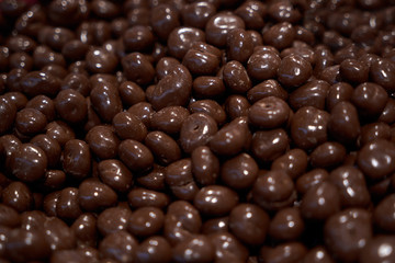 Almonds in chocolate glaze. Nuts in milk chocolate. Brown jelly beans dragee background. Candy shop.