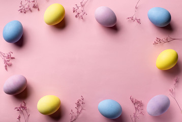 Stylish easter frame background with multicolored eggs and flowers on a pink background. horizontal image. top view, place for text