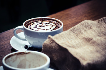 Close up of Hot coffee latte art with pattern on top, warm feeling coffee, vintage cup with coffee bean burlap