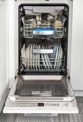 Open dishwasher with clean dishes in the white kitchen.