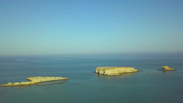 Panoramic view from the drone of the small rocky islands in the Persian Hall. Video made from Qeshm island, Iran. You can see the calm blue sea, horizon, cloudless sky. The camera moves back.