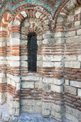 Old Town of Nesebar. Church of St. Paraskeva, XIII century. Stone facade of the church. Ceramic facade inserts. Typical brick and stone masonry, authentic patterns. Narrow window with bars