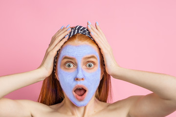 Beautiful woman with facial mask on pink background
