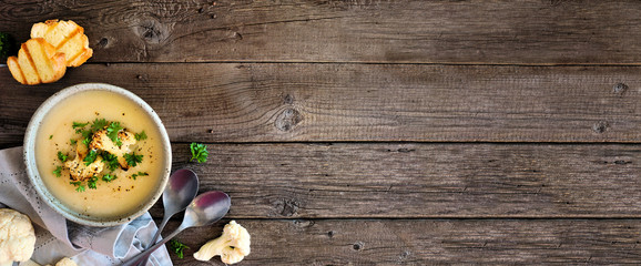 Fototapeta na wymiar Roasted cauliflower and potato and soup. Top view table scene. Banner with corner border over a rustic wood background with copy space.