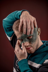 man with professional horror movie make-up green lizard on dark red background. lizard eye