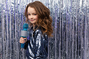 Obraz premium portrait of a girl with a microphone on a shiny background with copy space