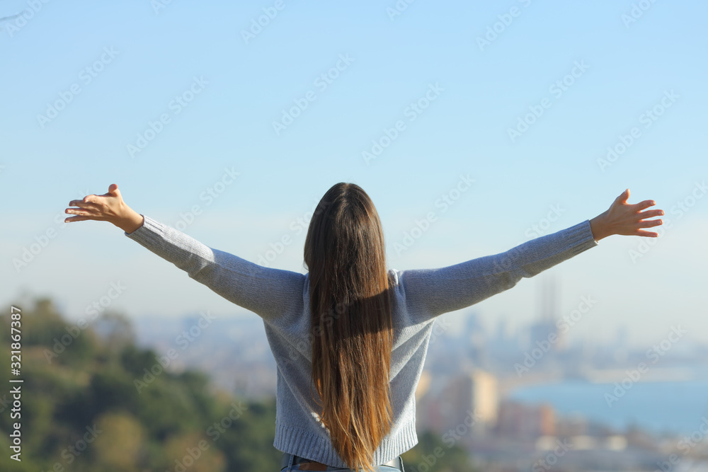 Wall mural woman stretching arms looking at city background