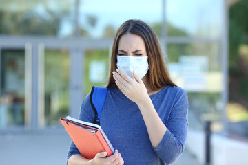 Ill student with a mask coughing in the stret