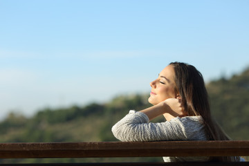 Woman sitting on a bench breathing fresh air in the mountain