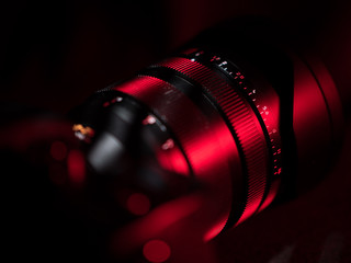 Fototapeta na wymiar camera lens on black background and red light
